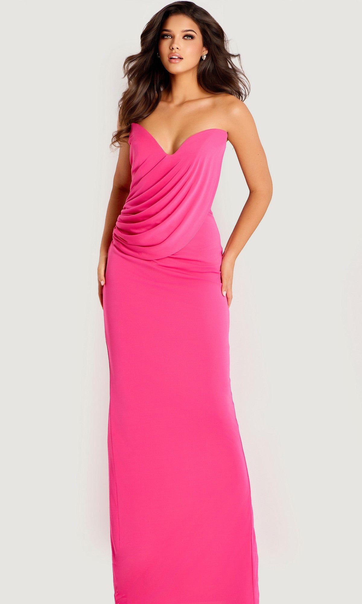 A woman poses against a plain light background wearing the Jovani 47831 Long Prom Dress, a strapless bright pink crepe gown with a draped bodice and floor-length fitted sheath silhouette.